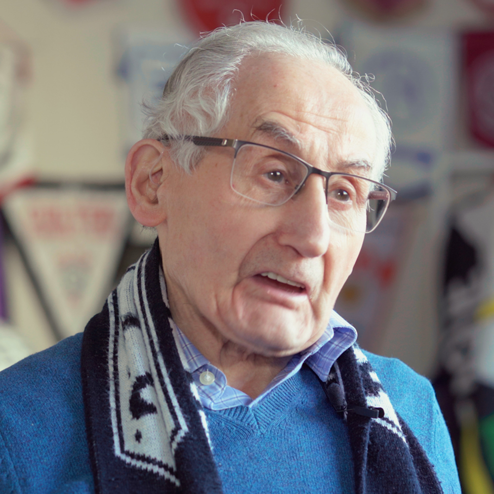 Older man in glasses and a football scarf, a still from a branded video