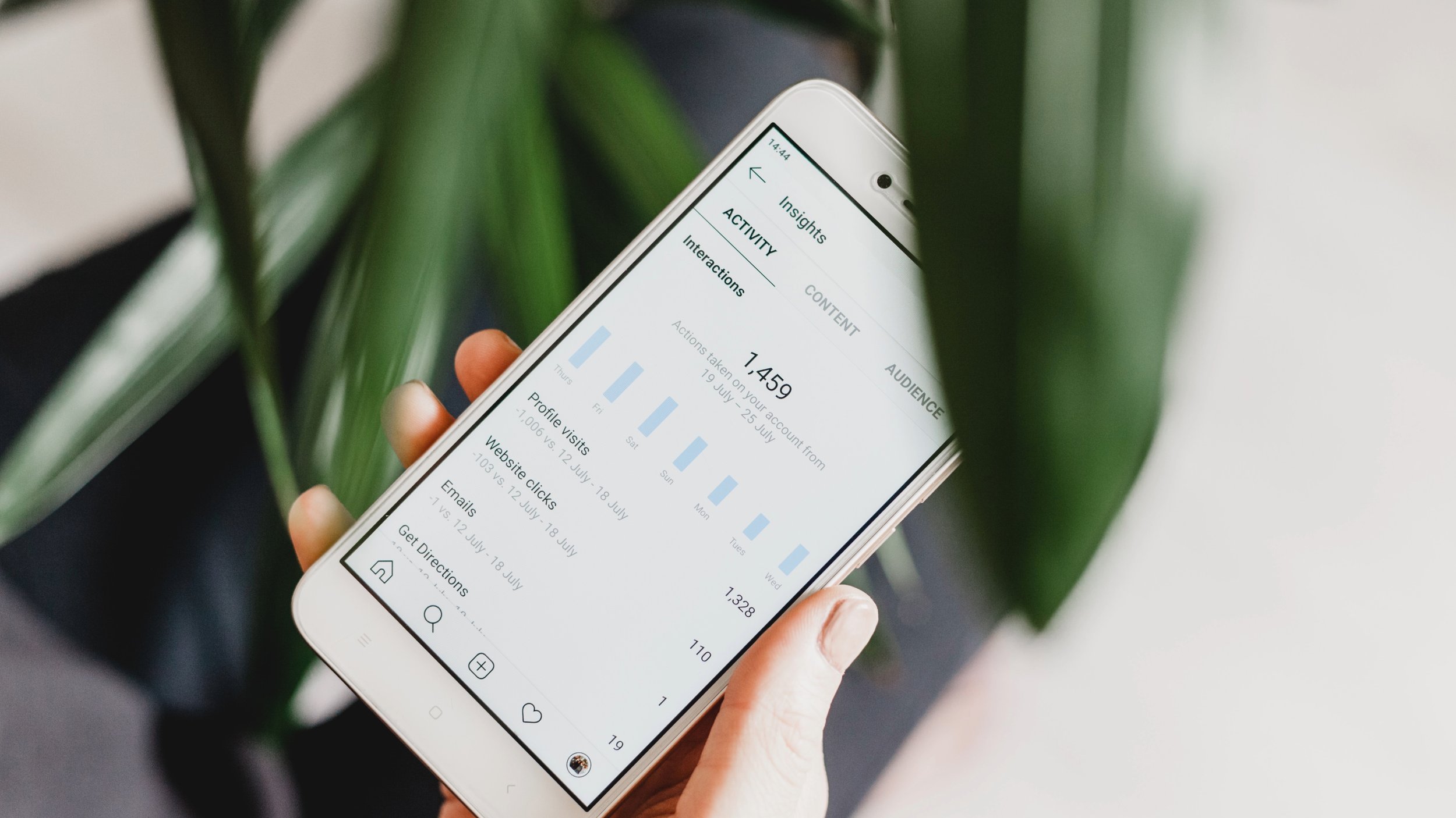 Hand holding a smartphone showing social media analytics
