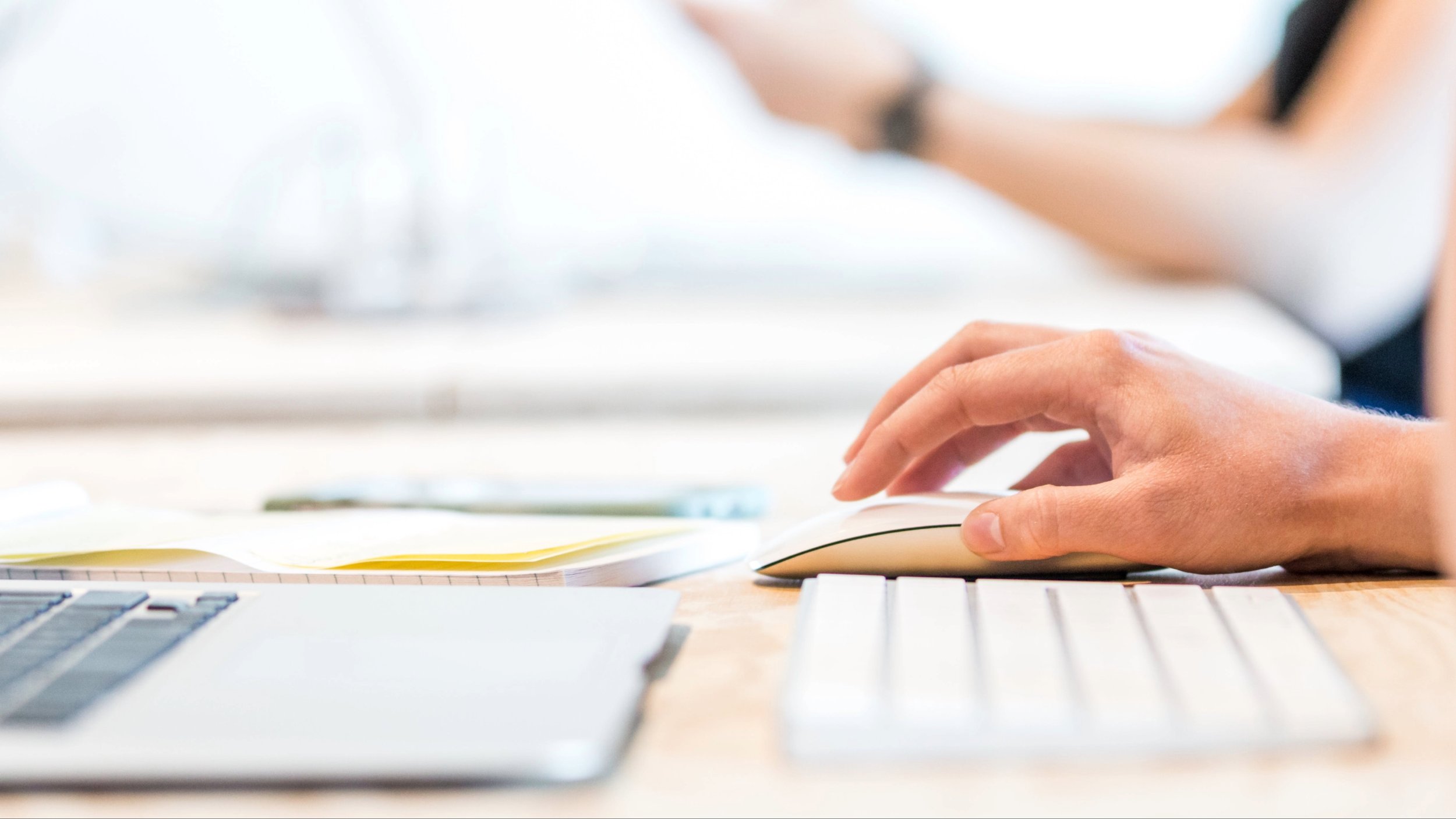 Hands typing on a keyboard at a bright desk