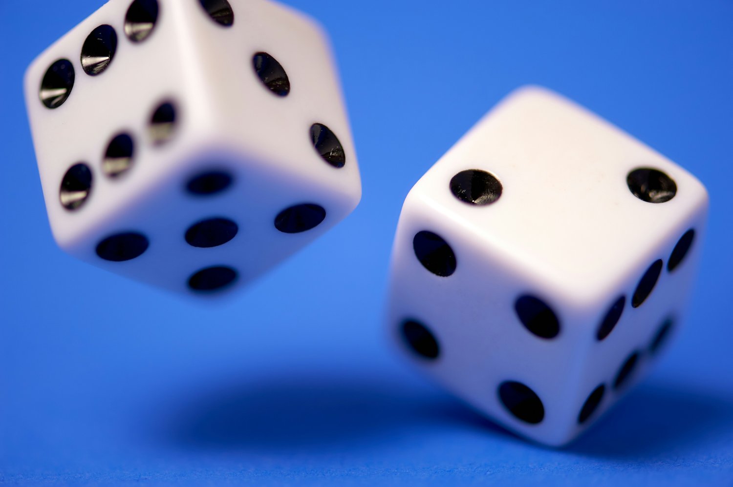Two white dice in mid-roll against a blue background