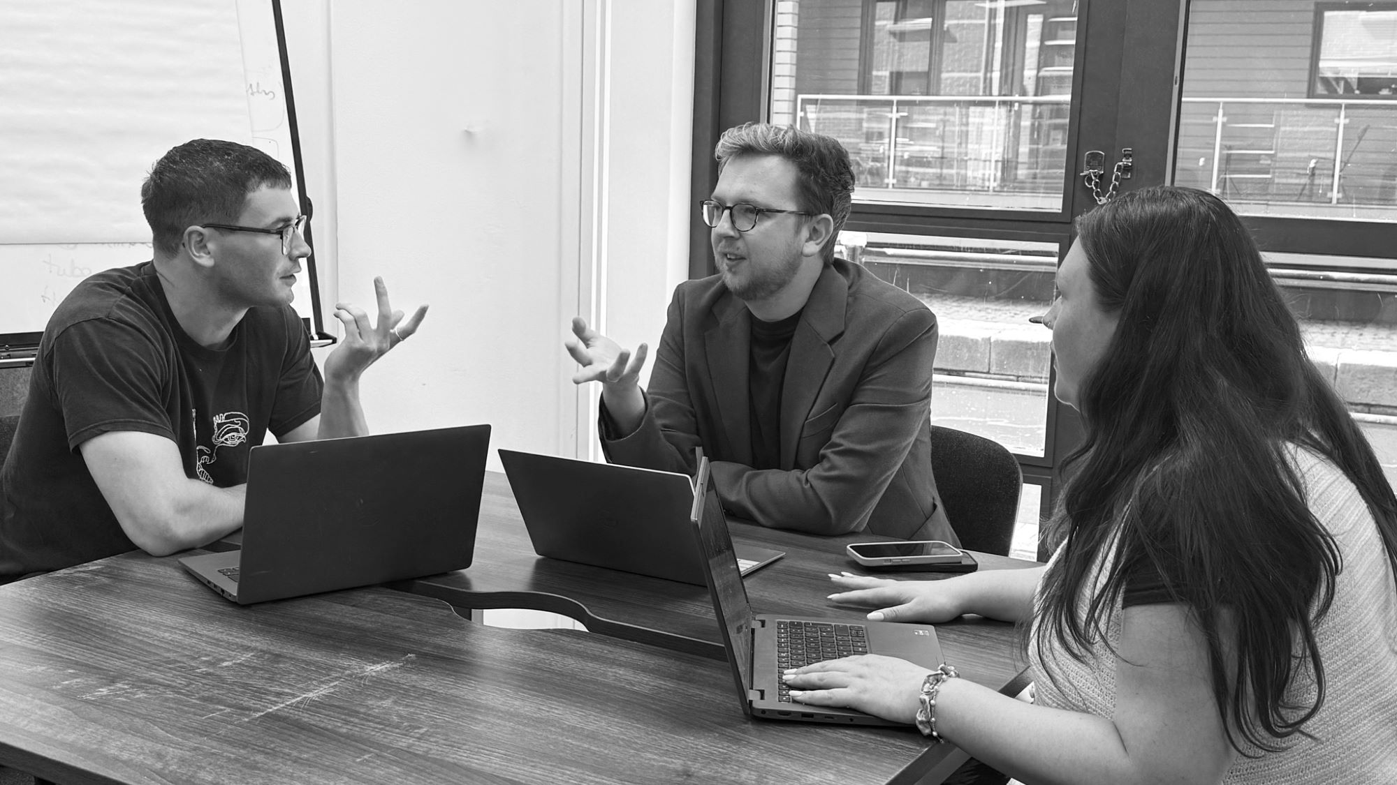 Tangerine team in a meeting around a table with laptops