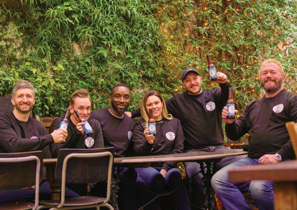 Group of six people in matching black shirts posing at an outdoor table