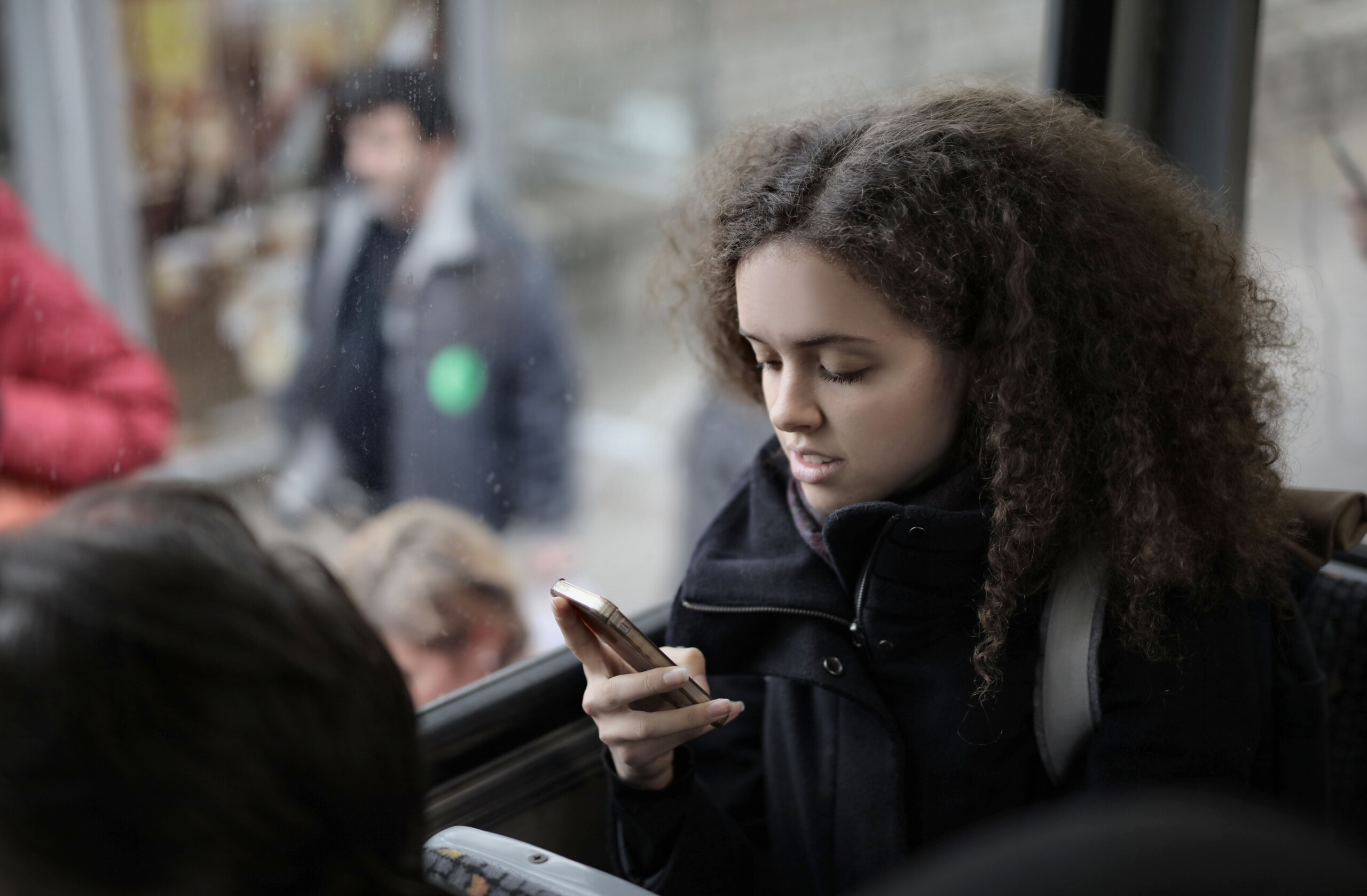 Teenager looking at a smartphone on a busy bus