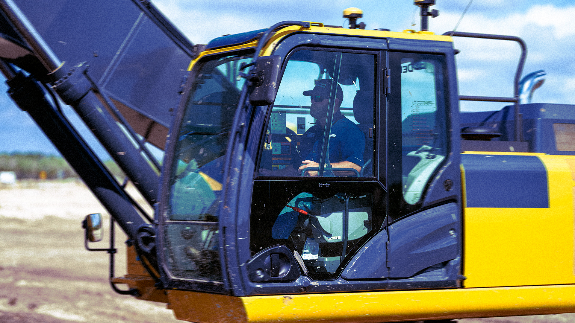 Operator in the cab of a yellow and blue excavator