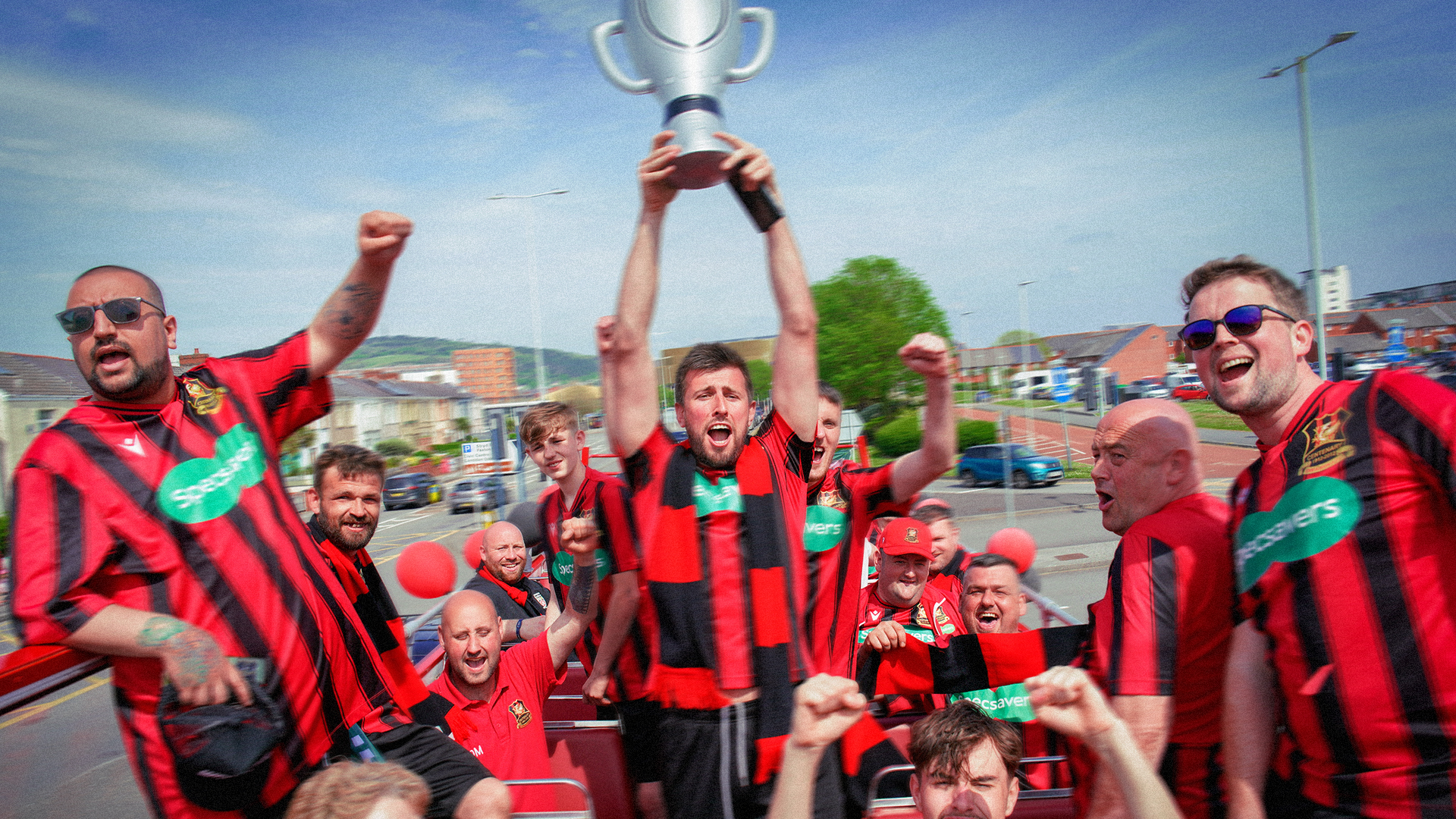 Team in red and black striped shirts lifting a trophy and celebrating
