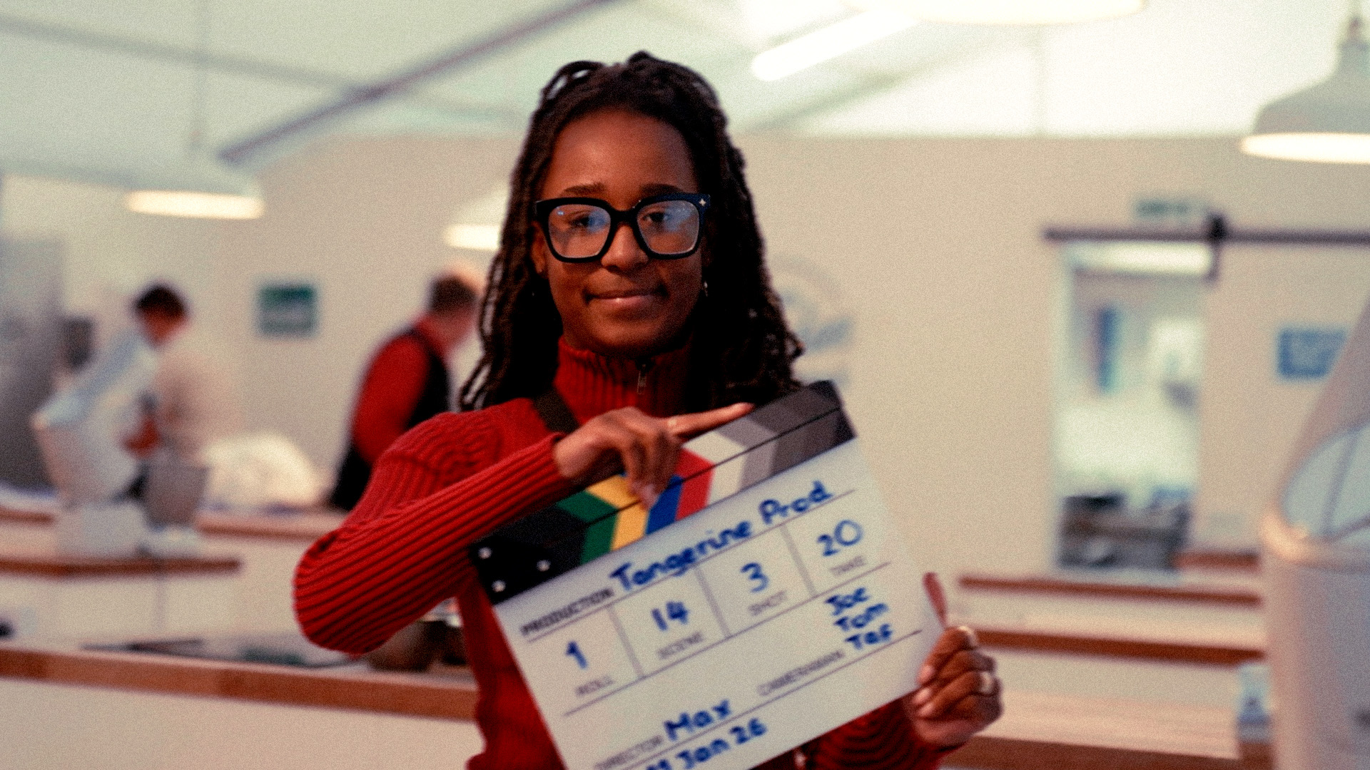 Tangerine apprentice holding a film clapperboard on a shoot