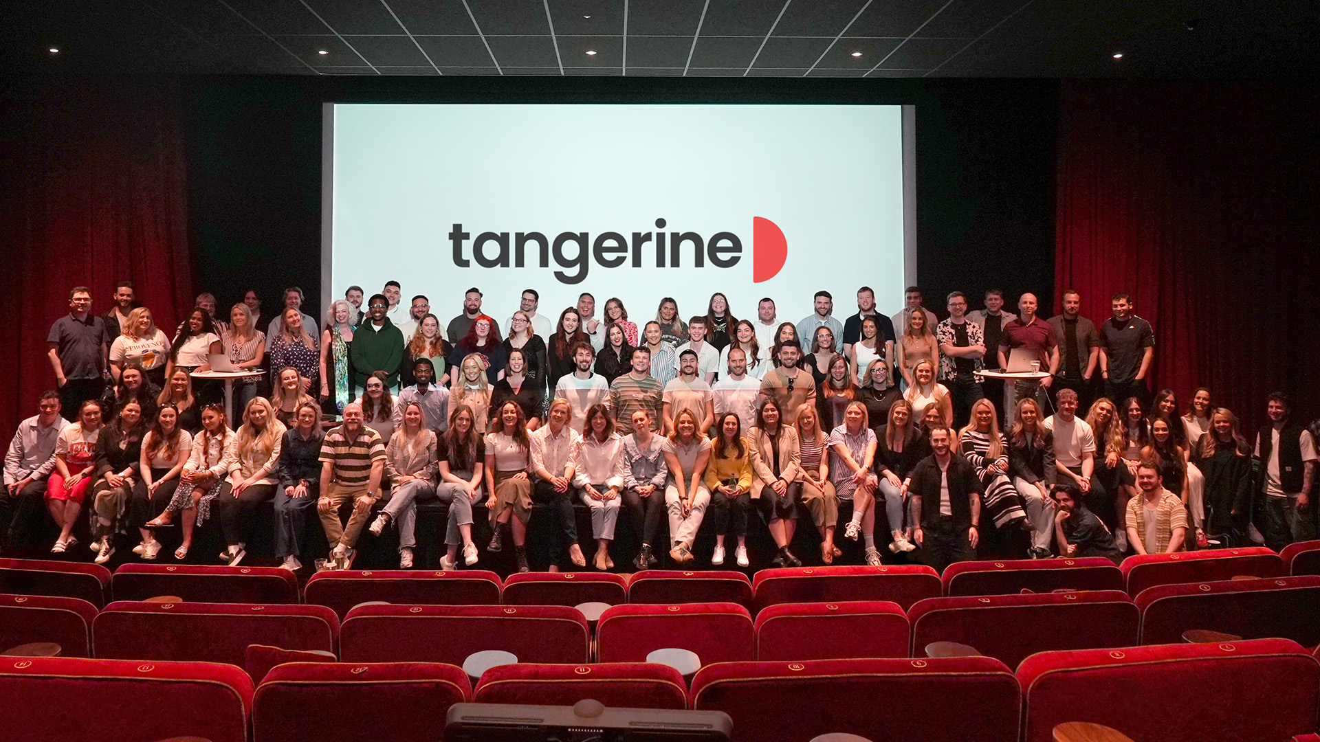 Tangerine team group photo in a cinema in front of the Tangerine logo