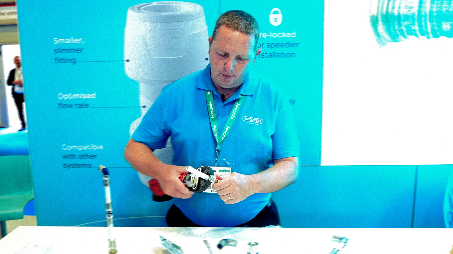 Wavin demonstrator showing plumbing fittings to the trade on an exhibition stand