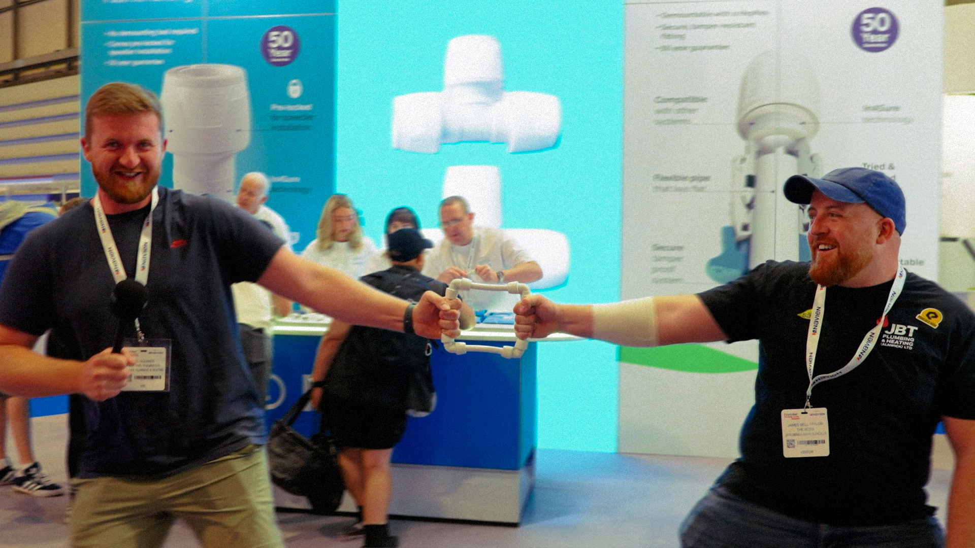 Two plumbers celebrating at the Wavin stand at a trade show